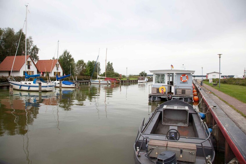 A calm canal with boats docked, a small house, and a lifebuoy on a boat. 5