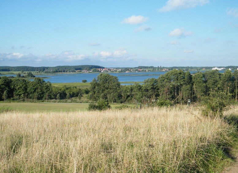 A landscape with a lake, trees, and a distant village. 3