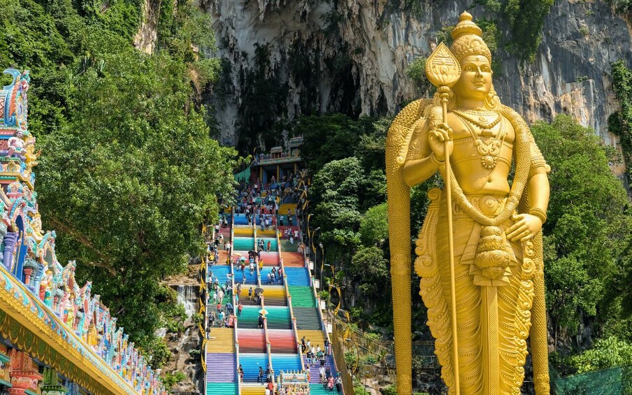 A large golden statue, colorful stairs, and a temple with intricate designs. 1