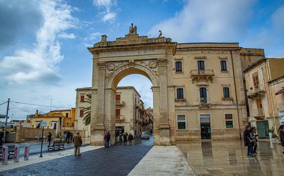 A historic archway in a city square with people walking around. 5