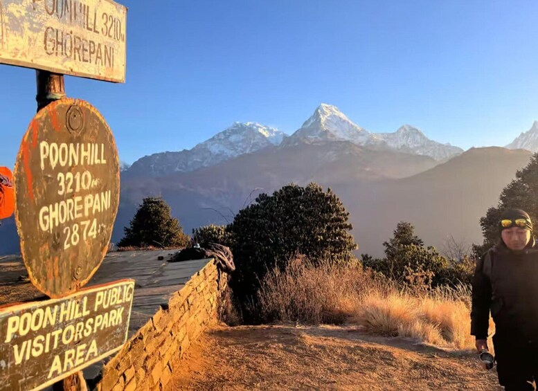 A mountain trail sign with 'Poon Hill 3210' and 'Ghorepani 2874' indicating elevation. 5