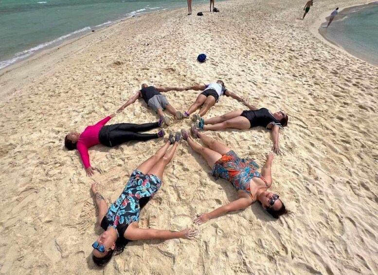 A group of people lying on a sandy beach in a circle. 2