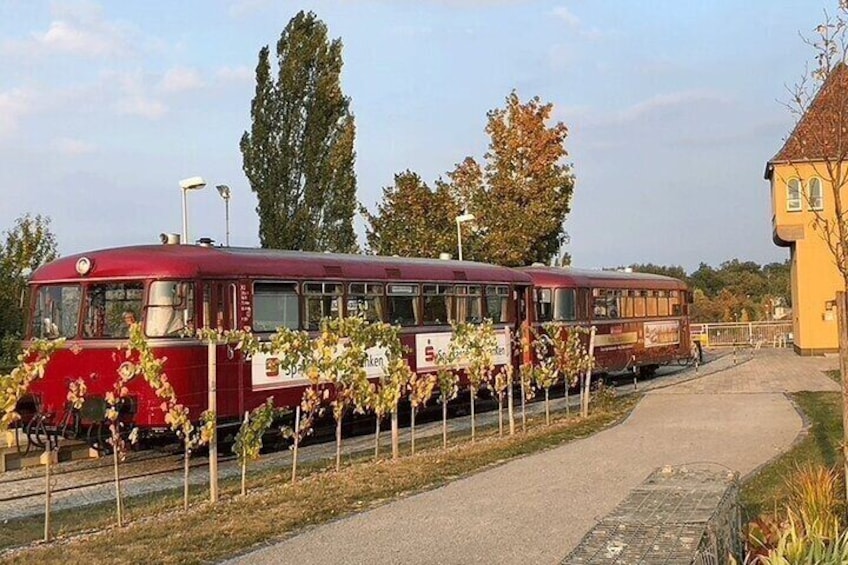 A vintage tram parked on a track with a building in the background. 4