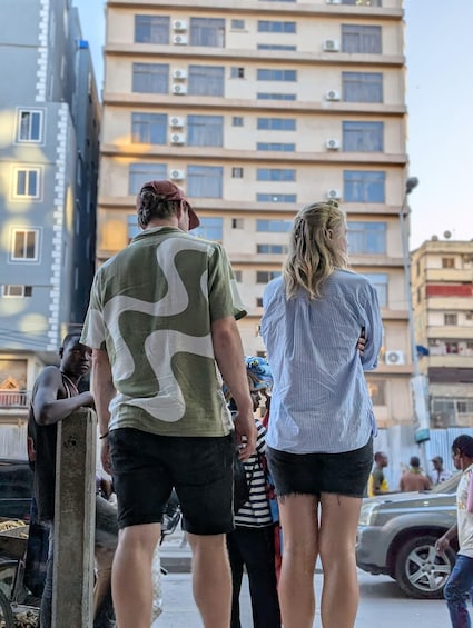 A group of people standing on a street with buildings in the background. 2