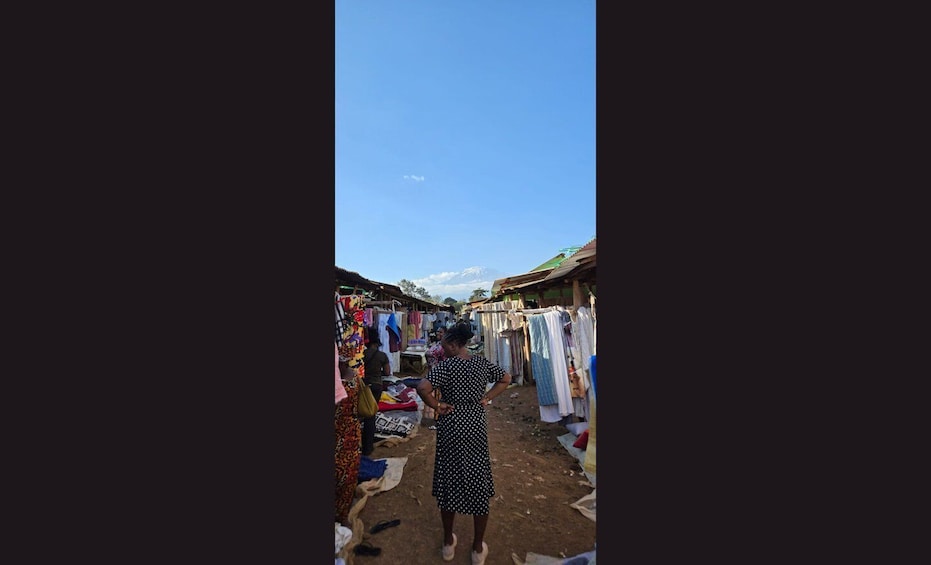 A narrow market street with stalls selling clothes and other goods. 1