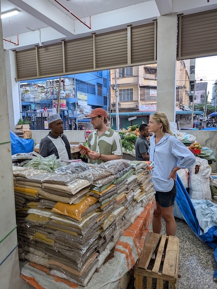 A market stall with various packaged goods, a person standing with hands on hips, and a cityscape in the background. 3