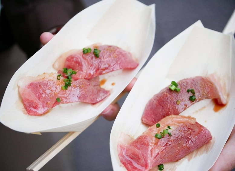 Two pieces of raw meat on white paper with green garnish. 3