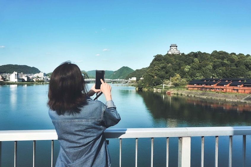 A person taking a photo of a castle on a hill overlooking a river. 4