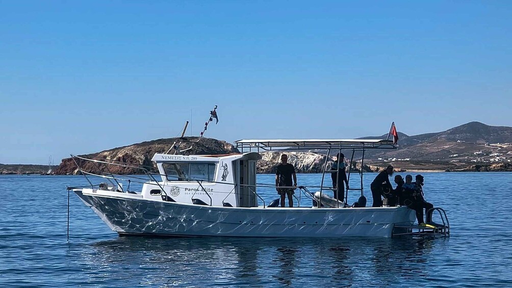 A boat with people on board, a rocky island in the background, and a clear blue sky. 2