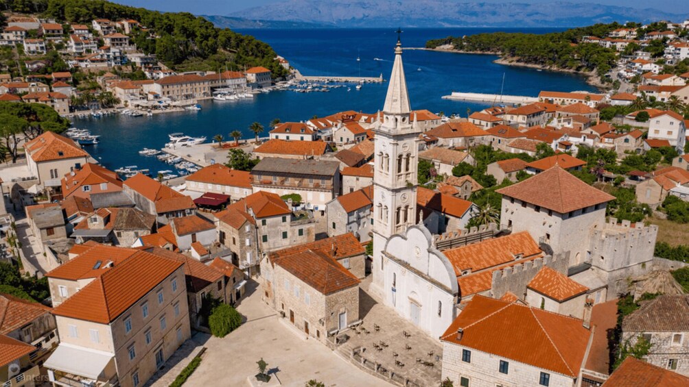 A coastal town with historic buildings, a prominent church tower, and a marina with boats. 3