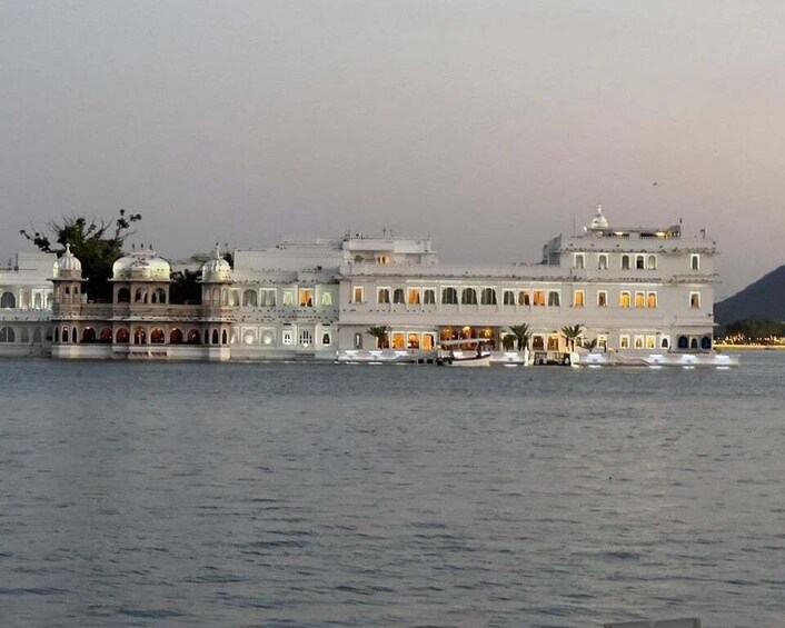 A large, white building with domes and arches by a body of water. 4
