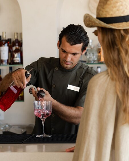 A bartender pouring a drink into a glass. 1