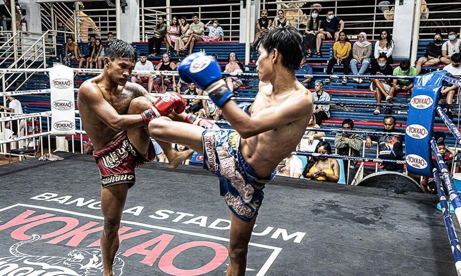Two fighters in a boxing ring with spectators in the background. 4