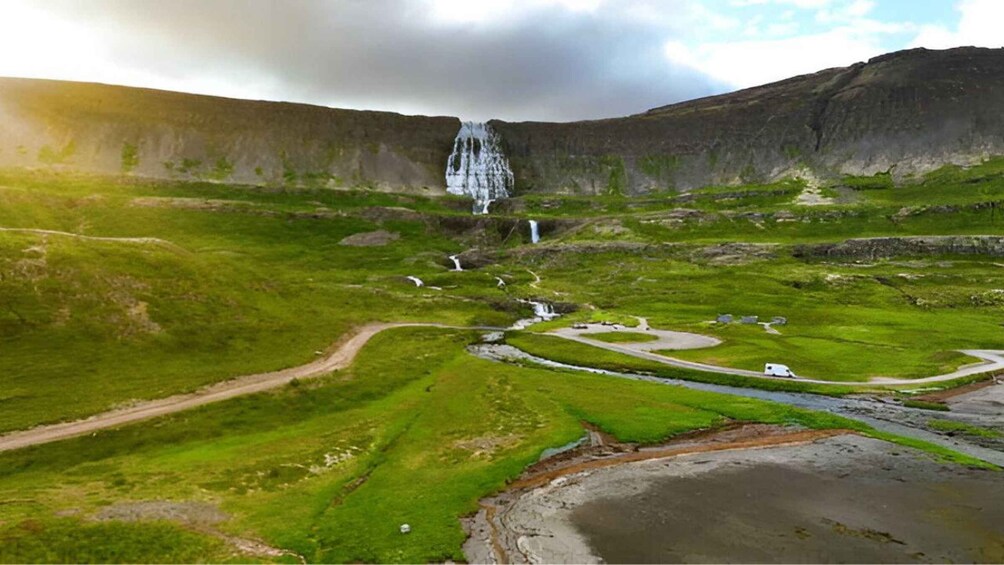 A landscape with a waterfall, green fields, and a winding road. 4