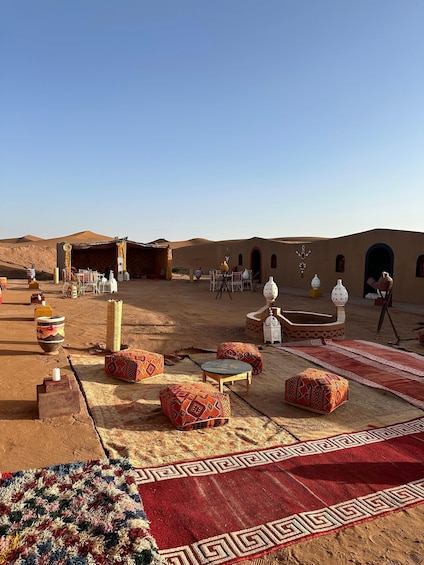 A desert courtyard with traditional seating, rugs, and decorative pottery. 2