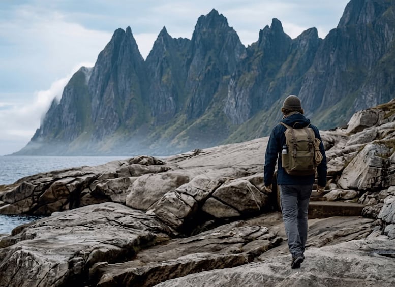 A hiker walking on rocky terrain with a mountainous backdrop. 1