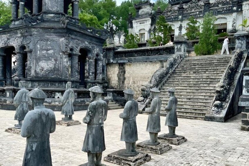 A historical site with stone statues, a temple structure, and a staircase. 2