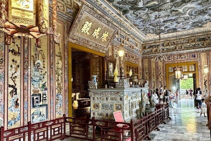 An ornate interior with intricate wall and ceiling decorations, a central altar, and a tiled floor. 4