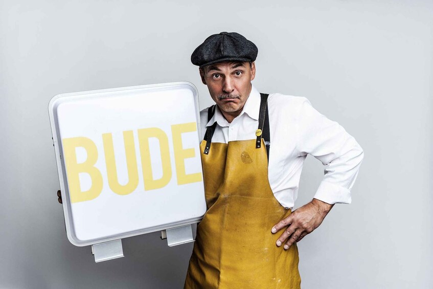 A person holding a sign that says "BUDE". 1
