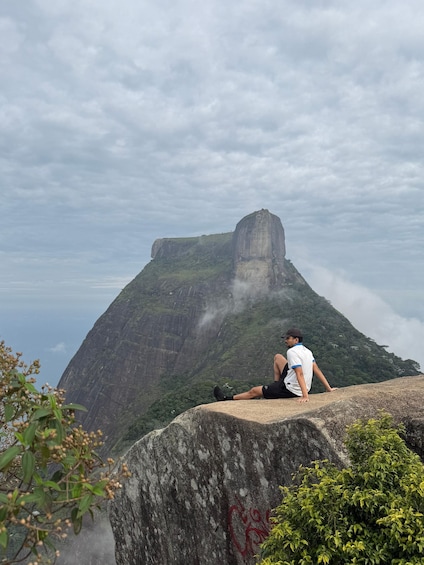 A person sitting on a rock with a mountain in the background. 5