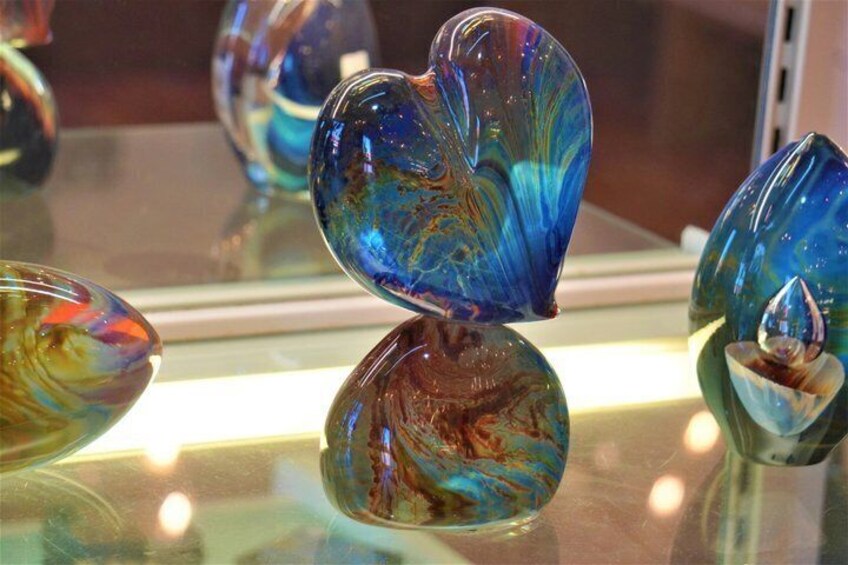 A collection of colorful glass heart-shaped objects displayed on a reflective surface. 3