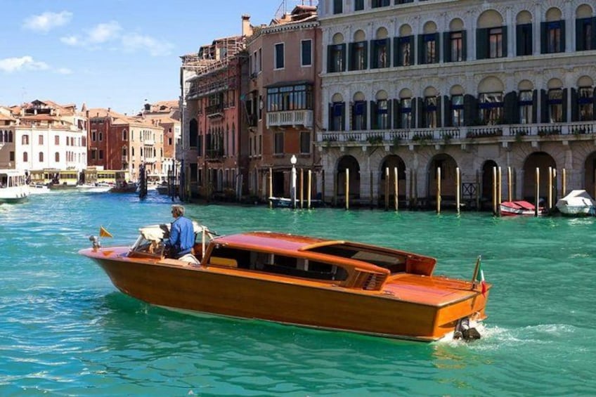 A wooden boat on Venetian canals with historic buildings in the background. 1