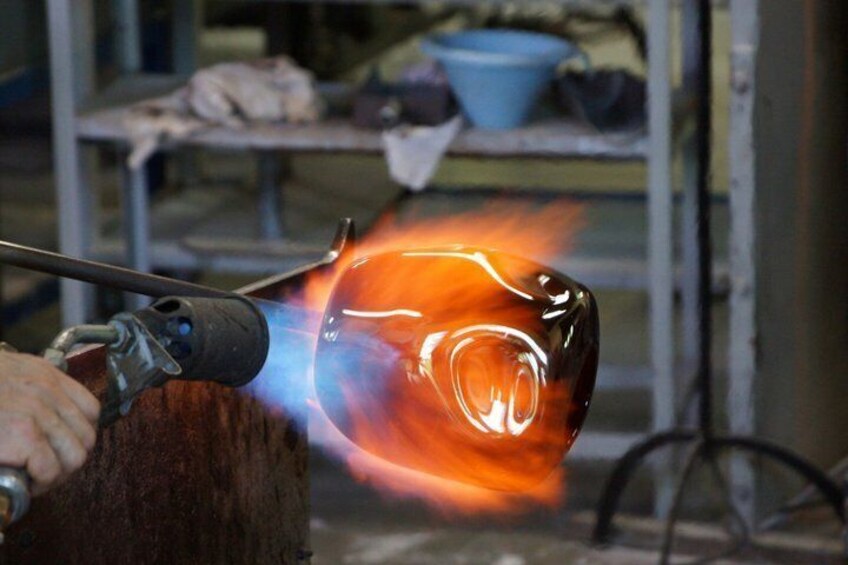 A glass blower shaping molten glass with a torch. 4