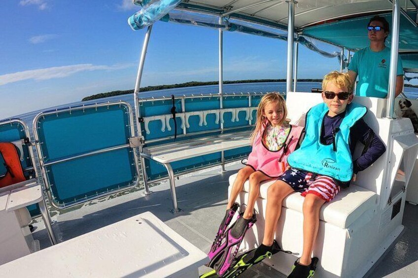 Two people on a boat with a clear view of the water and distant land. 3