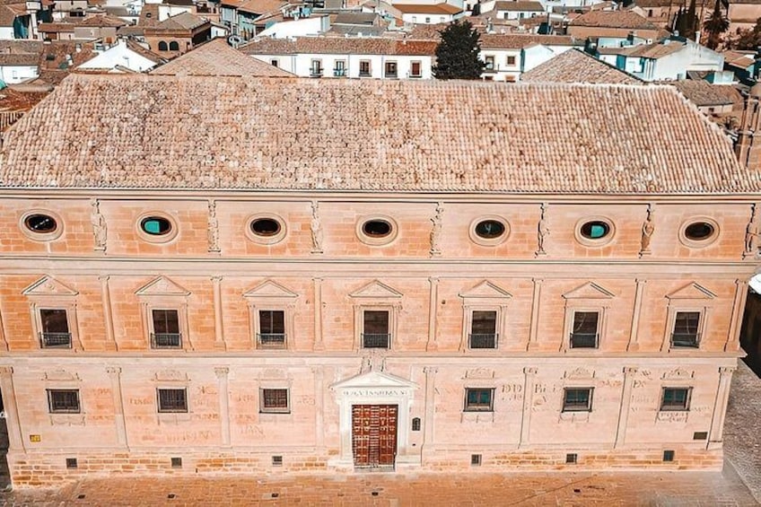 A historic building with a tiled roof, arched windows, and a central door. 3