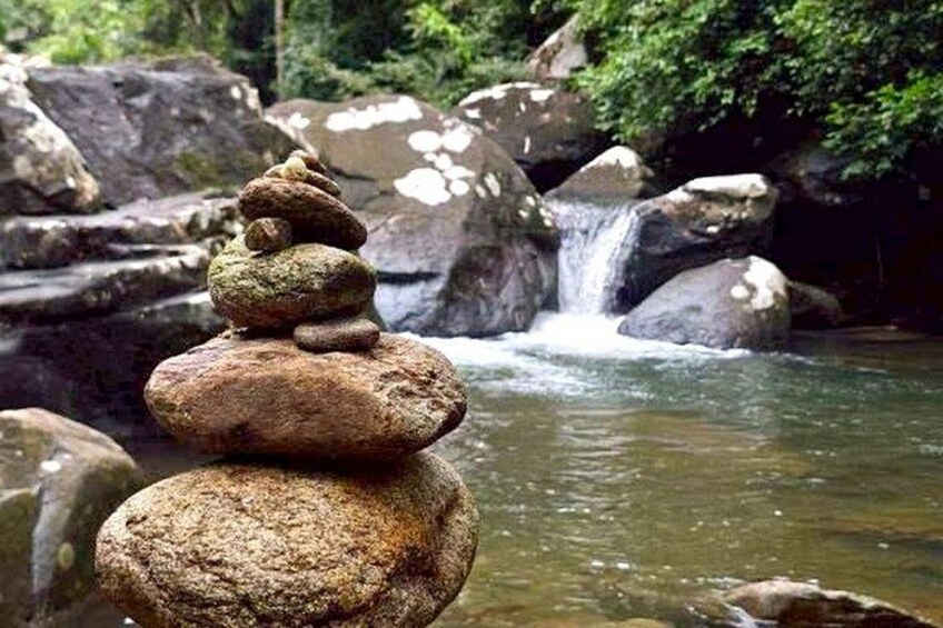 A stack of rocks in a natural setting with a waterfall in the background. 2