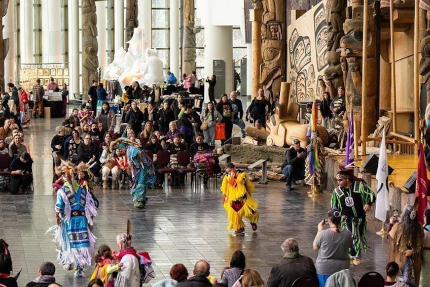 A cultural performance with dancers in traditional costumes in a large indoor space with stone columns and sculptures. 3