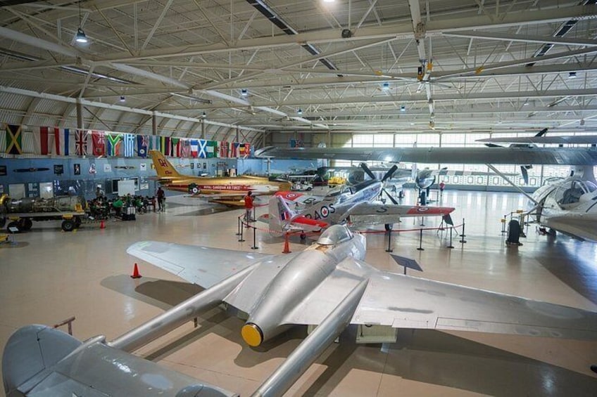 A museum with various aircraft on display, including a prominent red and white plane labeled 'MOGUL' and a yellow plane with 'Royal Air Force' markings. 2