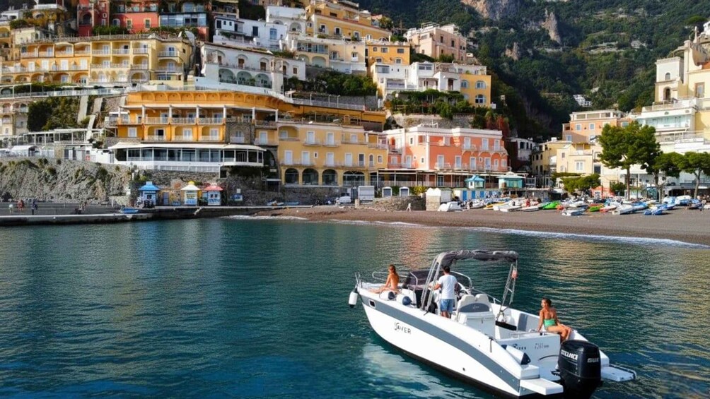 A coastal town with colorful buildings, a boat on the water, and a rocky shoreline. 1