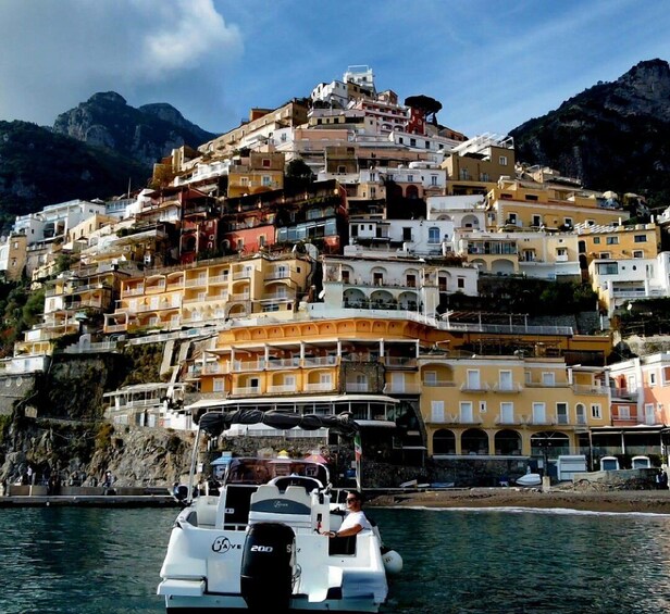 A coastal town with colorful buildings stacked on a hillside, a boat in the foreground, and mountains in the background. 5