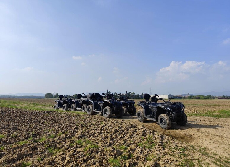 A row of ATVs parked on a dirt path in a rural field. 5