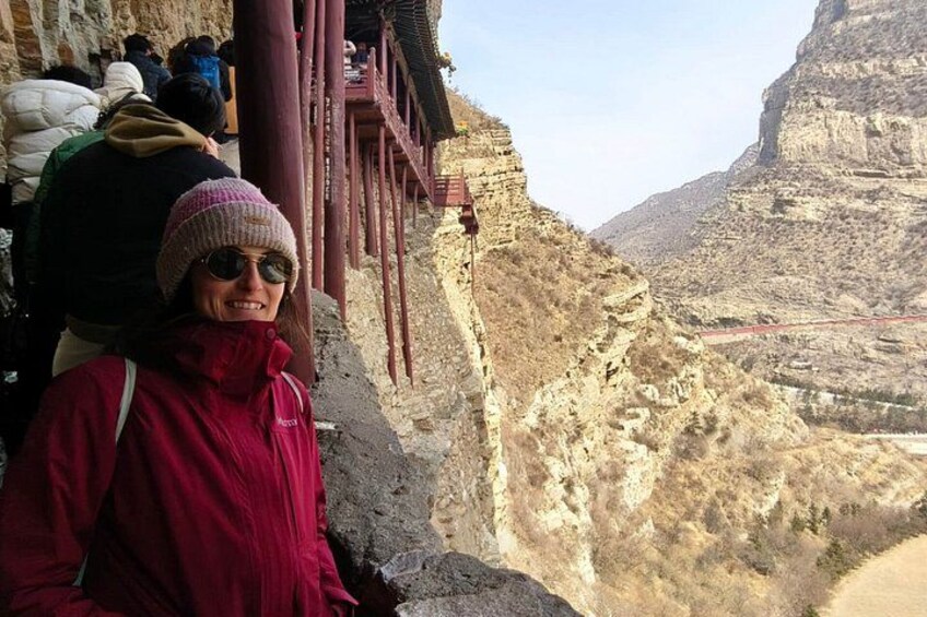 A person standing on a rocky ledge with a mountainous landscape in the background. 4