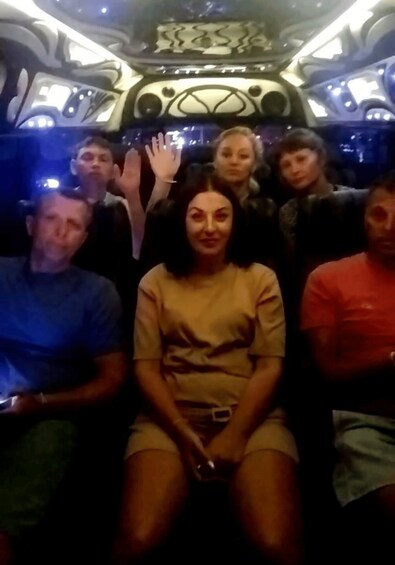 A group of people seated in a vehicle with a decorative interior. 3