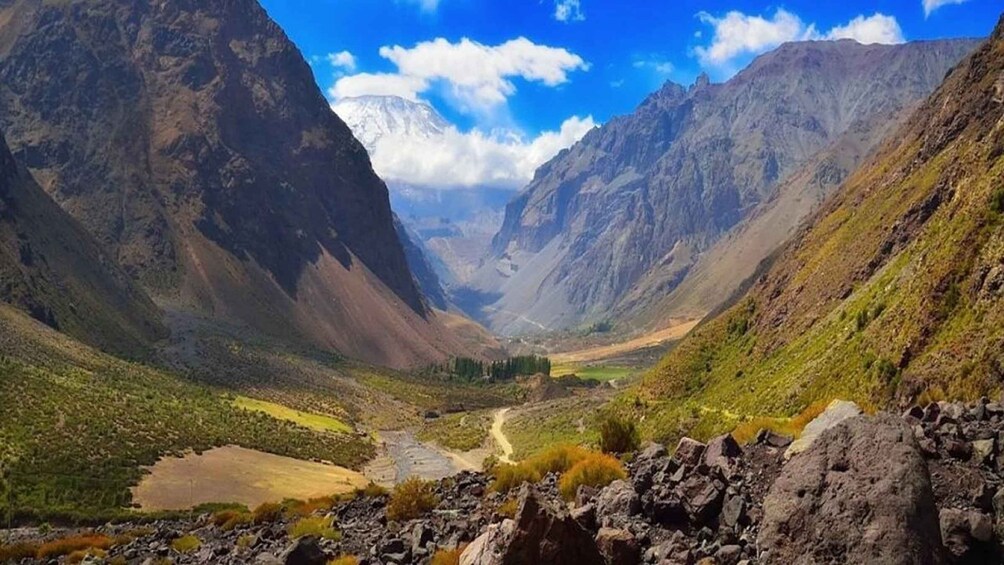 A mountainous landscape with a valley, rocky foreground, and a clear sky. 2