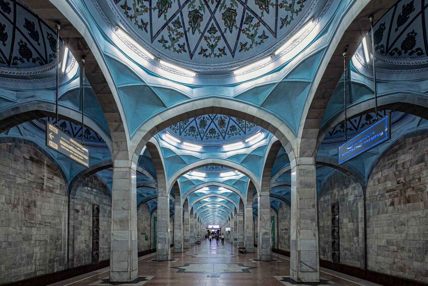 A grand, arched subway station with intricate ceiling designs and directional signs. 5