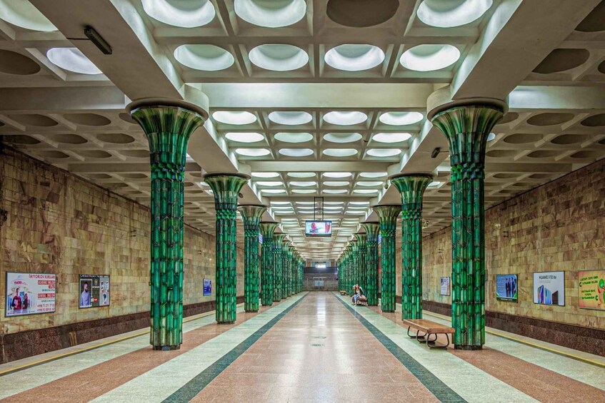 A subway station with green columns, tiled walls, and a ceiling with circular skylights. 1