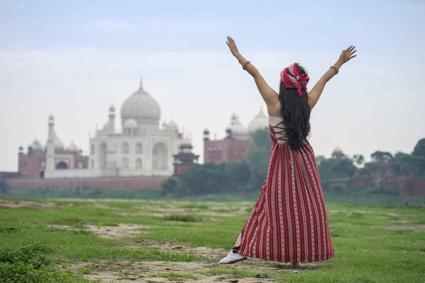 A person standing with arms raised in front of the Taj Mahal. 3