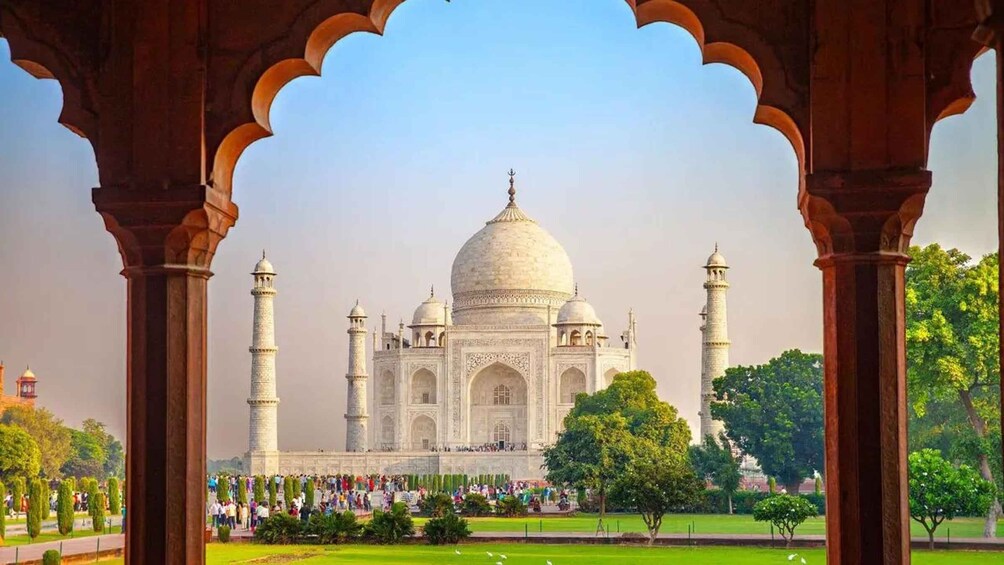 The Taj Mahal with a clear sky, surrounded by greenery and a crowd of people. 1