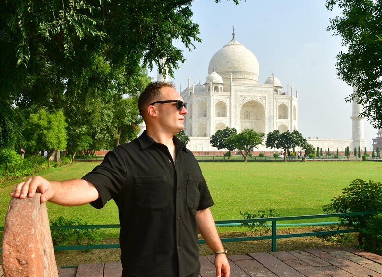 A person standing with a railing, overlooking the Taj Mahal. 5