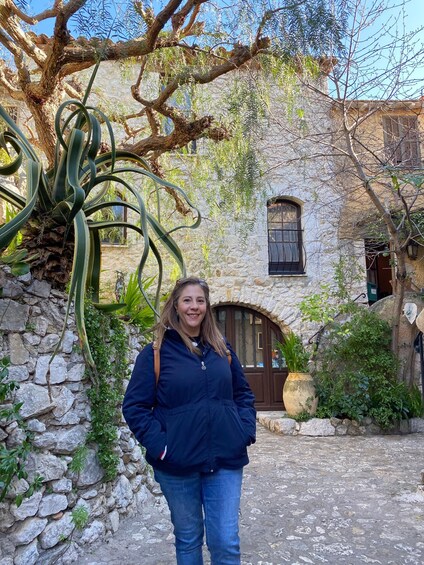 A person standing in front of a stone building with a window and a door. 4