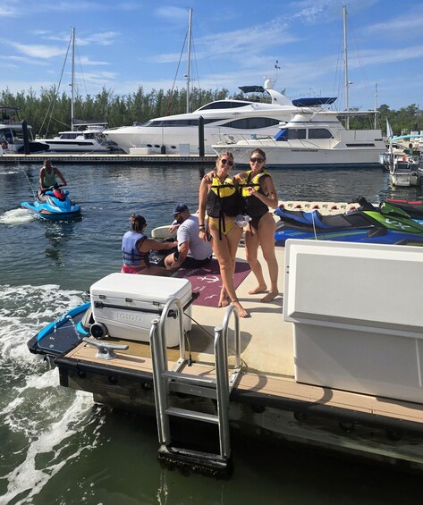 A marina with boats docked, a jet ski in motion, and people on a boat. 4