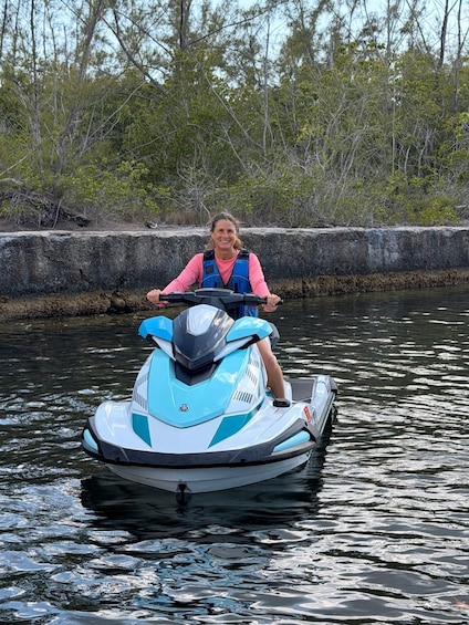 A person riding a jet ski on calm water with trees in the background. 5