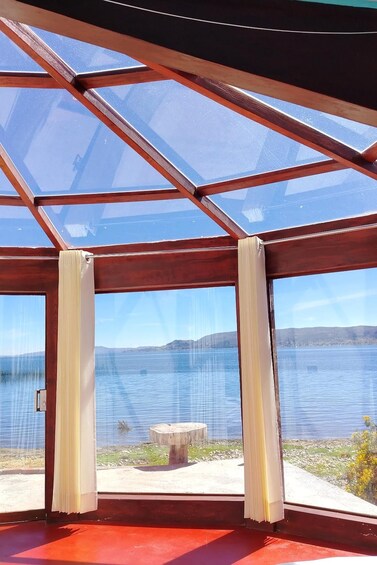 A glass-paneled room with a view of a lake and distant hills. 4