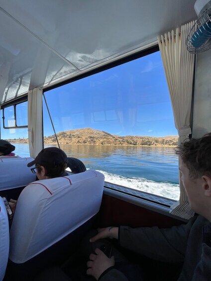 A boat with passengers looking out at a calm lake and distant hills. 5