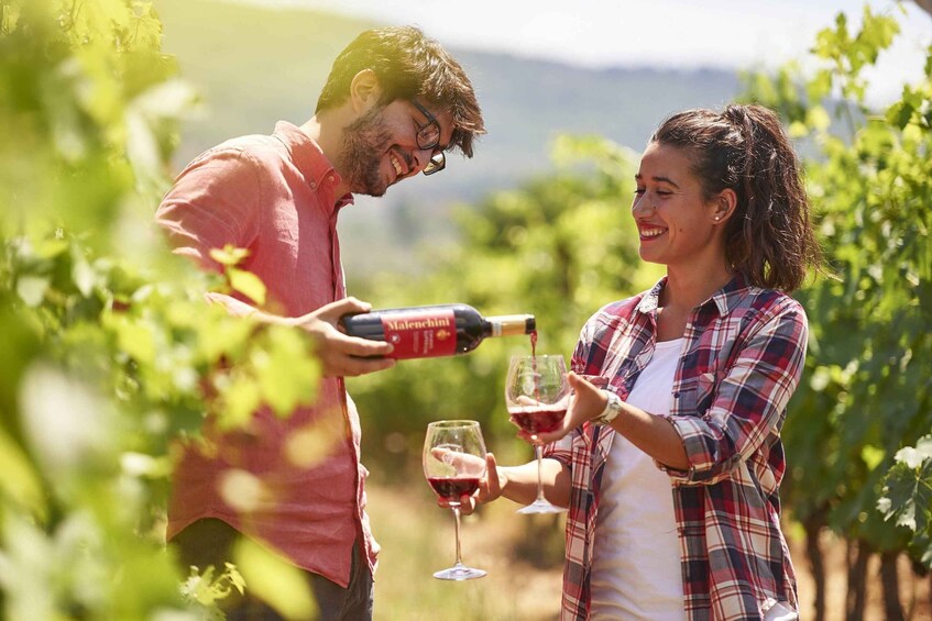 Two people in a vineyard holding wine glasses and a wine bottle. 2
