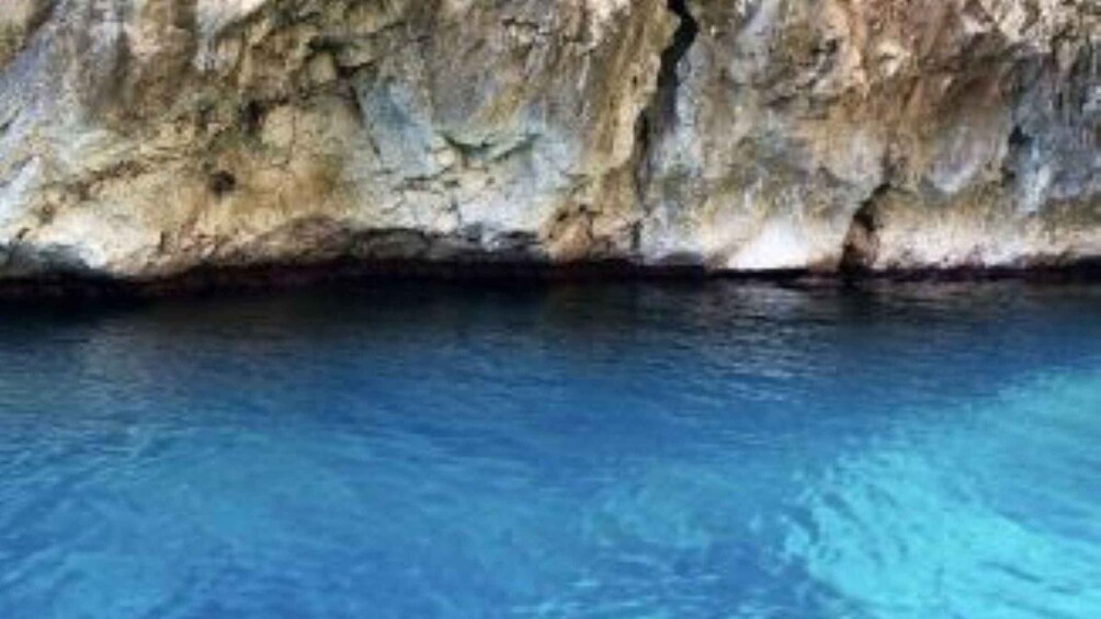 A clear blue pool with a rocky cliff in the background. 4